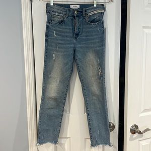 Medium wash pistola jeans with frayed bottoms and side zipper